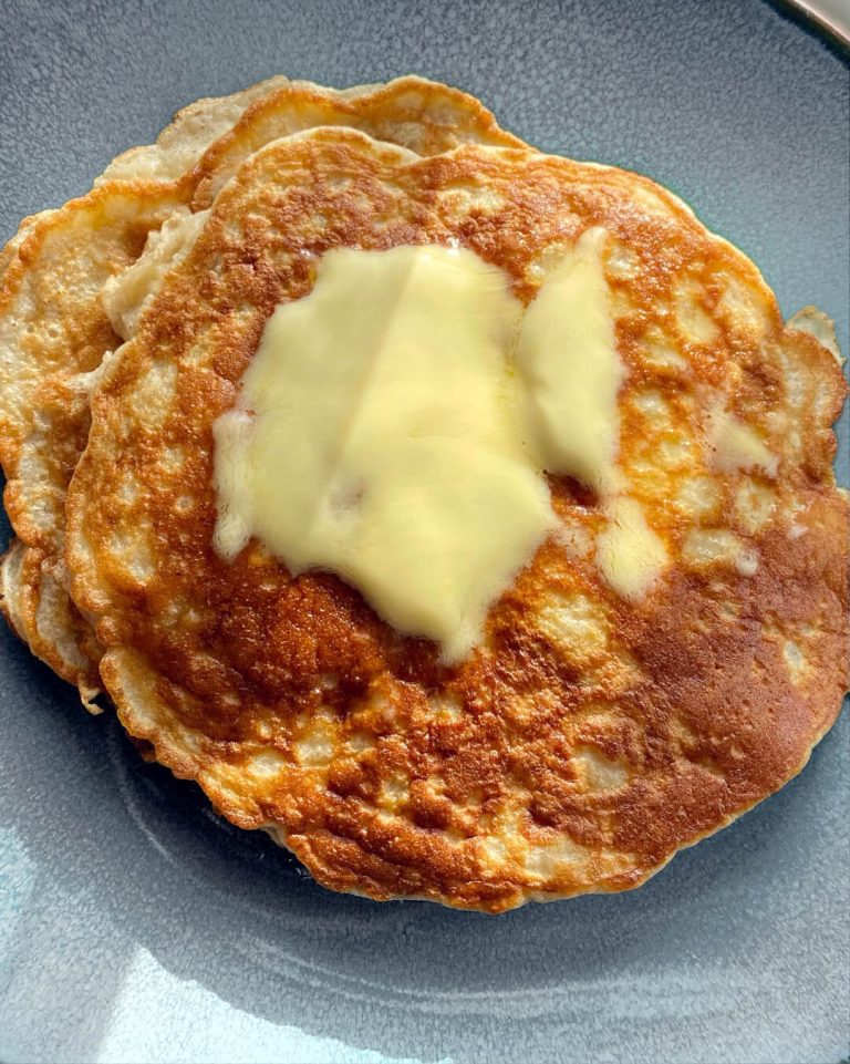 Une pile de pancakes sans gluten sur une assiette a dessert, avec un peu de margarine fondue sur le dessus