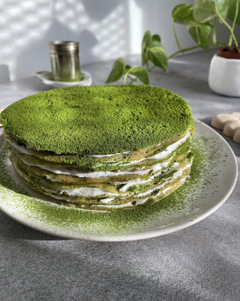Gâteau mille crepe au thé matcha sans gluten, disposé sur un plat et saupoudré de poudre de matcha