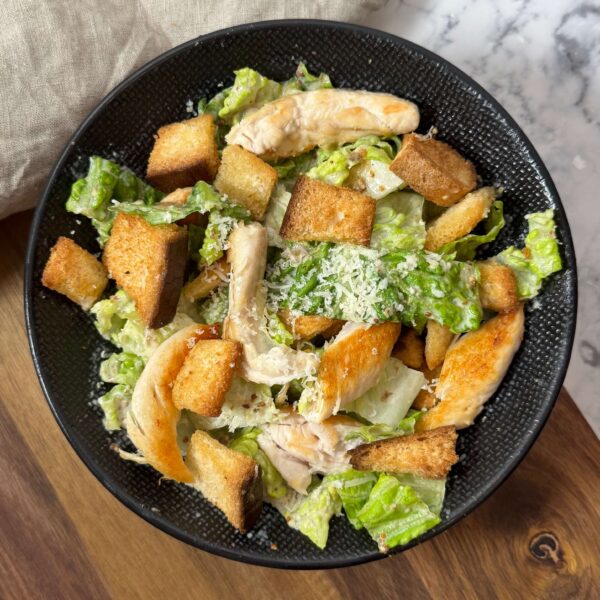Salade césar disposée dans une assiette creuse de couleur noire