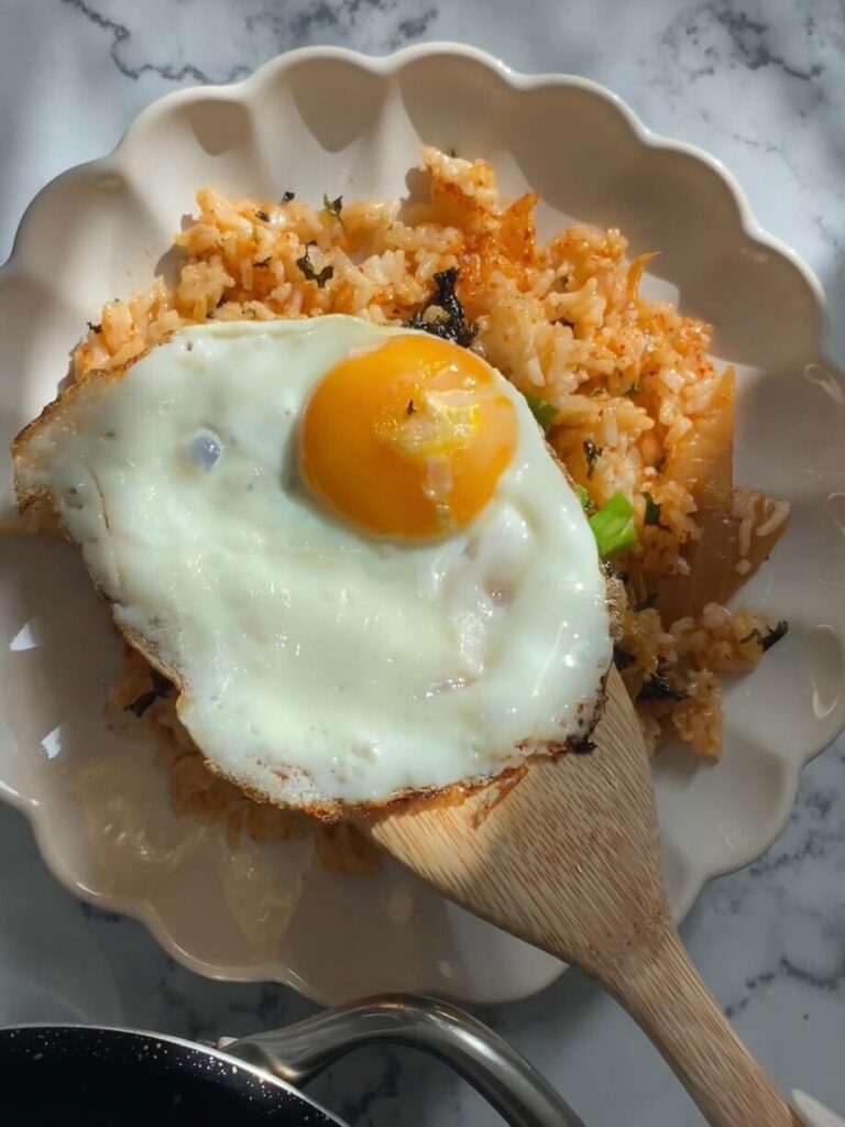 On dispose un œuf sur le plat sur une assiette de riz frit coréen tout juste servie