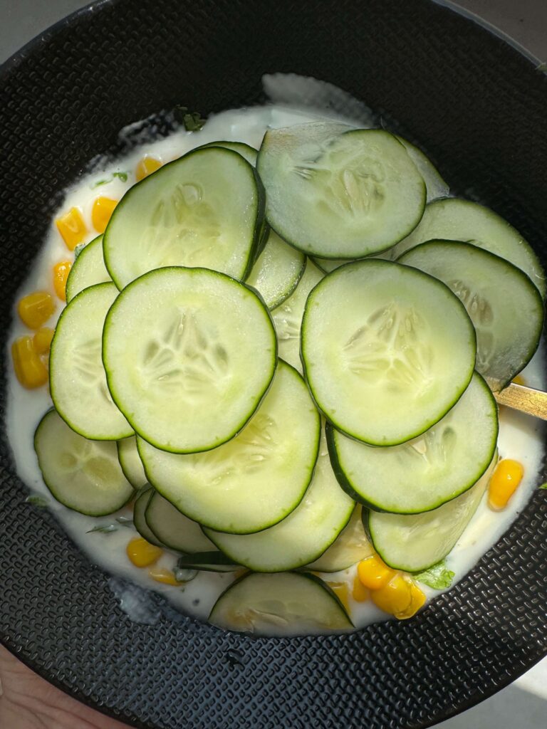 Dans un bol, du maïs et du concombre coupé en rondelles pour la préparation de la salade de maïs