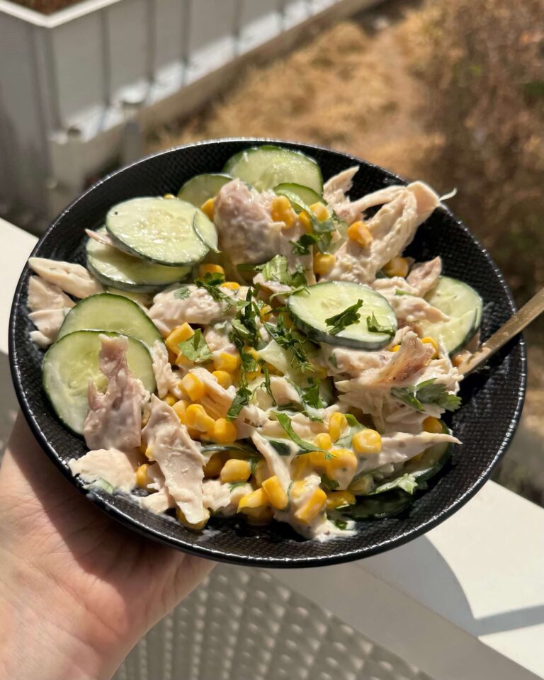 Sur un balcon ensoleillé, assiette de salade de maïs au poulet et au concombre